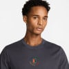 Ein Mann in einem dunklen T-Shirt mit Nike Court-Logo auf der Brust.