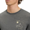 Ein Mann trägt ein dunkelgraues T-Shirt mit Bergmotiv und Koordinaten.