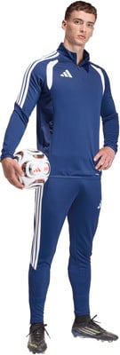 Ein Mann im dunkelblauen Trainingsanzug mit weißen Streifen hält einen Fußball. Ein Mann im dunkelblauen Trainingsanzug mit weißen Streifen hält einen Fußball.