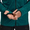 Ein Mann passt die Ärmel einer dunkelgrünen Jacke mit Daumenlöchern an.