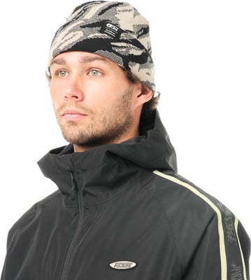 Ein junger Mann in einer schwarzen Kapuzenjacke und einer Camouflage-Mütze mit Logo. Ein junger Mann in einer schwarzen Kapuzenjacke und einer Camouflage-Mütze mit Logo.
