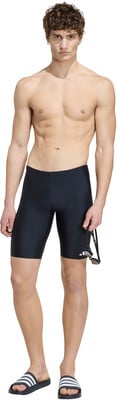 Ein Mann in schwarzen Badeshorts und Sandalen hält eine Schwimmbrille. Ein Mann in schwarzen Badeshorts und Sandalen hält eine Schwimmbrille.