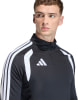 Ein Mann in einem schwarzen Oberteil mit weißen Streifen an den Schultern und Adidas-Logo.