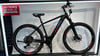 Schwarzes Genesis E-Bike mit roten und blauen Akzenten auf Rahmen und Rädern.