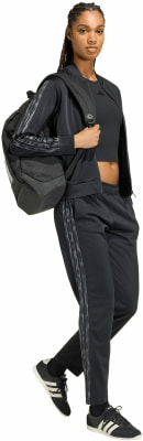Eine Frau in schwarzer Adidas-Kleidung mit Rucksack und Turnschuhen. Eine Frau in schwarzer Adidas-Kleidung mit Rucksack und Turnschuhen.