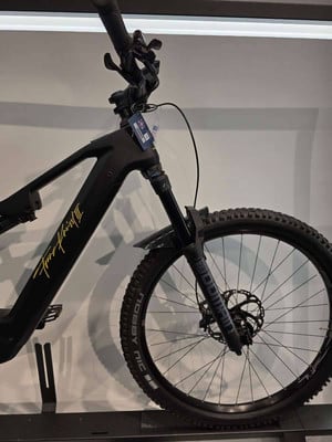Schwarzes Mountain-E-Bike mit gelbem Schriftzug und Federgabel. Schwarzes Mountain-E-Bike mit gelbem Schriftzug und Federgabel.