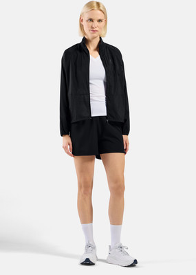 Eine Frau in schwarzer Sportkleidung mit weißem T-Shirt und weißen Turnschuhen.