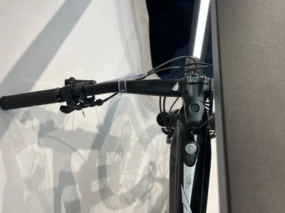 Detail des Lenkers und der Vorderseite eines schwarzen Mountainbikes mit weißen Elementen. Detail des Lenkers und der Vorderseite eines schwarzen Mountainbikes mit weißen Elementen.