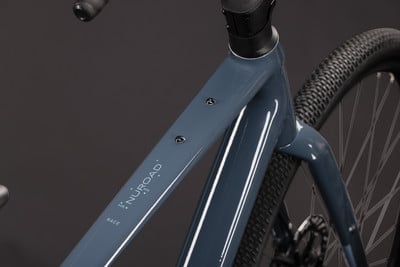 Detail eines grauen Gravelbike-Rahmens mit der Aufschrift NUROAD RACE. Detail eines grauen Gravelbike-Rahmens mit der Aufschrift NUROAD RACE.