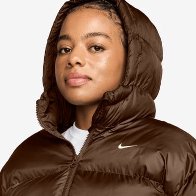 Frau in brauner Daunenjacke mit Kapuze und Nike-Logo.