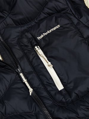 Detail einer schwarzen Daunenjacke mit Peak Performance Logo und Reißverschluss.