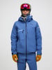 Ein Skifahrer präsentiert eine blaue Jacke und Hose mit Helm und Brille.