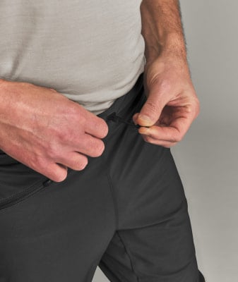 Ein Mann zieht die Kordel an seiner schwarzen Hose fest.