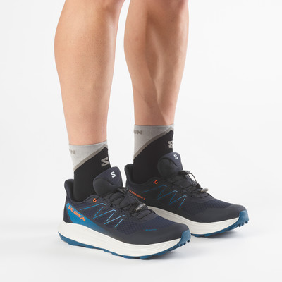 Nahaufnahme von Füßen in dunkelblauen Salomon-Laufschuhen mit grauen Socken. Nahaufnahme von Füßen in dunkelblauen Salomon-Laufschuhen mit grauen Socken.