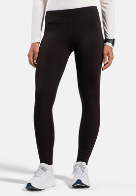 Eine Frau in dunklen Leggings und weißen Sneakern steht vor weißem Hintergrund. Eine Frau in dunklen Leggings und weißen Sneakern steht vor weißem Hintergrund.
