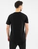 Mann von hinten in einem schwarzen T-Shirt und Jogginghose auf weißem Grund.