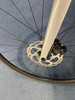 Detail eines Fahrrad-Vorderrads mit Scheibenbremse und Gabel.