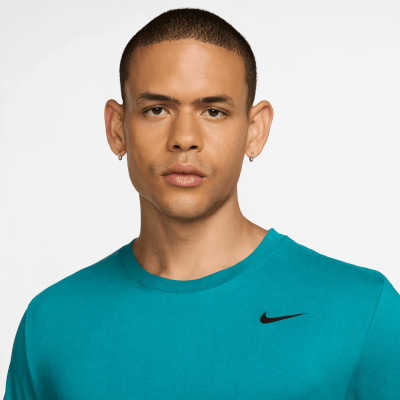 Ein Mann in einem blaugrünen T-Shirt mit Nike-Logo vor weißem Hintergrund. Ein Mann in einem blaugrünen T-Shirt mit Nike-Logo vor weißem Hintergrund.