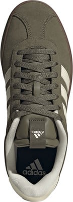 Grüne Adidas Sneaker mit weißen Streifen und brauner Sohle.