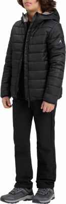 Ein Junge in einer schwarzen Daunenjacke und Hose steht vor weißem Hintergrund. Ein Junge in einer schwarzen Daunenjacke und Hose steht vor weißem Hintergrund.