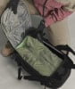 Eine Person packt eine grüne Jacke und Handschuhe in einen Rucksack.