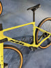 Ein gelbes KTM Gravelbike mit orangefarbenen Reifen auf blauem Untergrund.