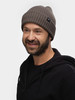 Ein Mann mit grauem Beanie und schwarzem Hoodie lächelt.