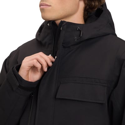 Ein Mann schließt eine schwarze Jacke mit Kapuze und Brusttaschen. Ein Mann schließt eine schwarze Jacke mit Kapuze und Brusttaschen.