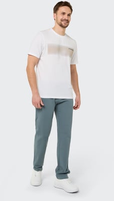 Ein Mann in einem weißen T-Shirt mit Aufdruck und blauer Hose steht vor weißem Hintergrund. Ein Mann in einem weißen T-Shirt mit Aufdruck und blauer Hose steht vor weißem Hintergrund.