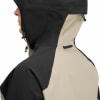 Detail einer Kapuzenjacke aus schwarzem und beigem Stoff, von der Seite gezeigt.