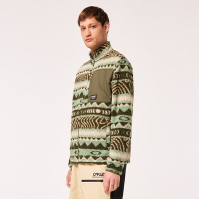 Ein Mann in einem Fleece-Pullover mit ethnischem Muster und grüner Tasche.