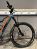 Graues Mountain-E-Bike mit orangefarbenen Details und Federung vorne.