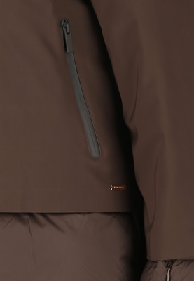 Detail einer Jacke mit dunklem Reißverschlussfach und Markenlogo. Detail einer Jacke mit dunklem Reißverschlussfach und Markenlogo.