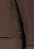 Detail einer Jacke mit dunklem Reißverschlussfach und Markenlogo.