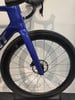 Detail eines blauen Rennrads mit Vorderrad und Gabel.