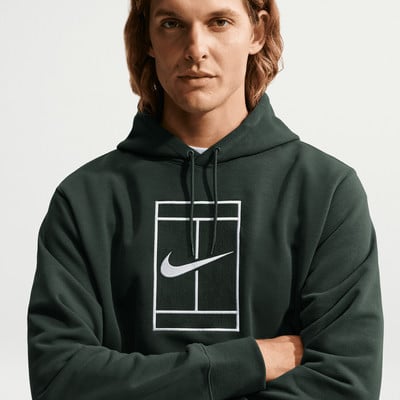 Ein Mann in einem dunkelgrünen Kapuzenpullover mit Nike-Logo auf einem Tennisplatz. Ein Mann in einem dunkelgrünen Kapuzenpullover mit Nike-Logo auf einem Tennisplatz.