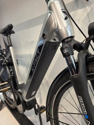 Nahaufnahme eines E-Bikes mit X-FACT-Logo am Rahmen und Federgabel. Nahaufnahme eines E-Bikes mit X-FACT-Logo am Rahmen und Federgabel.