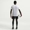Rückansicht eines Fußballers im weißen Trikot und schwarzer Hose mit Ball.