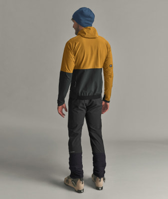 Ein Mann in einer Kapuzenjacke, Hose und Skischuhen vor neutralem Hintergrund. Ein Mann in einer Kapuzenjacke, Hose und Skischuhen vor neutralem Hintergrund.