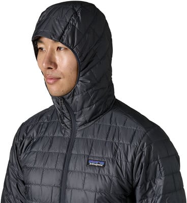 Ein Mann in einer dunklen Steppjacke mit Kapuze und Patagonia-Logo auf der Brust.