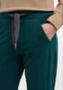 Detail einer dunkelgrünen Jogginghose mit Tasche und Kordelzug.