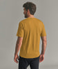 Ein Mann in einem senfgelben T-Shirt und schwarzer Hose, von hinten.