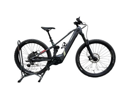 Graues E-Mountainbike auf Ständer mit Federung und Scheibenbremsen.