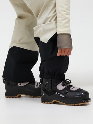 Schwarzer Atomic-Skischuh mit beige-schwarzer Hose. Schwarzer Atomic-Skischuh mit beige-schwarzer Hose.