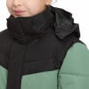 Ein Mädchen trägt eine schwarz-grüne Daunenjacke mit Kapuze.