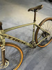 Ein grünes Trek Gravelbike mit goldenen Felgen und schwarzem Sattel.