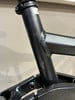 Detail eines Fahrradrahmens mit leichten Abnutzungen und Kratzern auf dunklem Metallic-Finish.