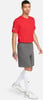 Ein Mann in einem roten T-Shirt und grauen Shorts mit weißen Socken und Turnschuhen.