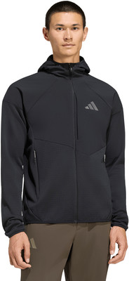 Ein Mann in einem schwarzen Kapuzenpullover und einer Khaki-Hose mit Adidas-Logo. Ein Mann in einem schwarzen Kapuzenpullover und einer Khaki-Hose mit Adidas-Logo.