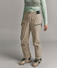 Model in beige Hose und Skischuhen auf grauem Hintergrund.